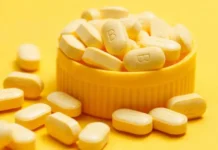 Can Nutritional Deficiencies Lead to Hair Loss? Pile of yellow oblong tablets spilling from a yellow bottle cap on a bright yellow background.